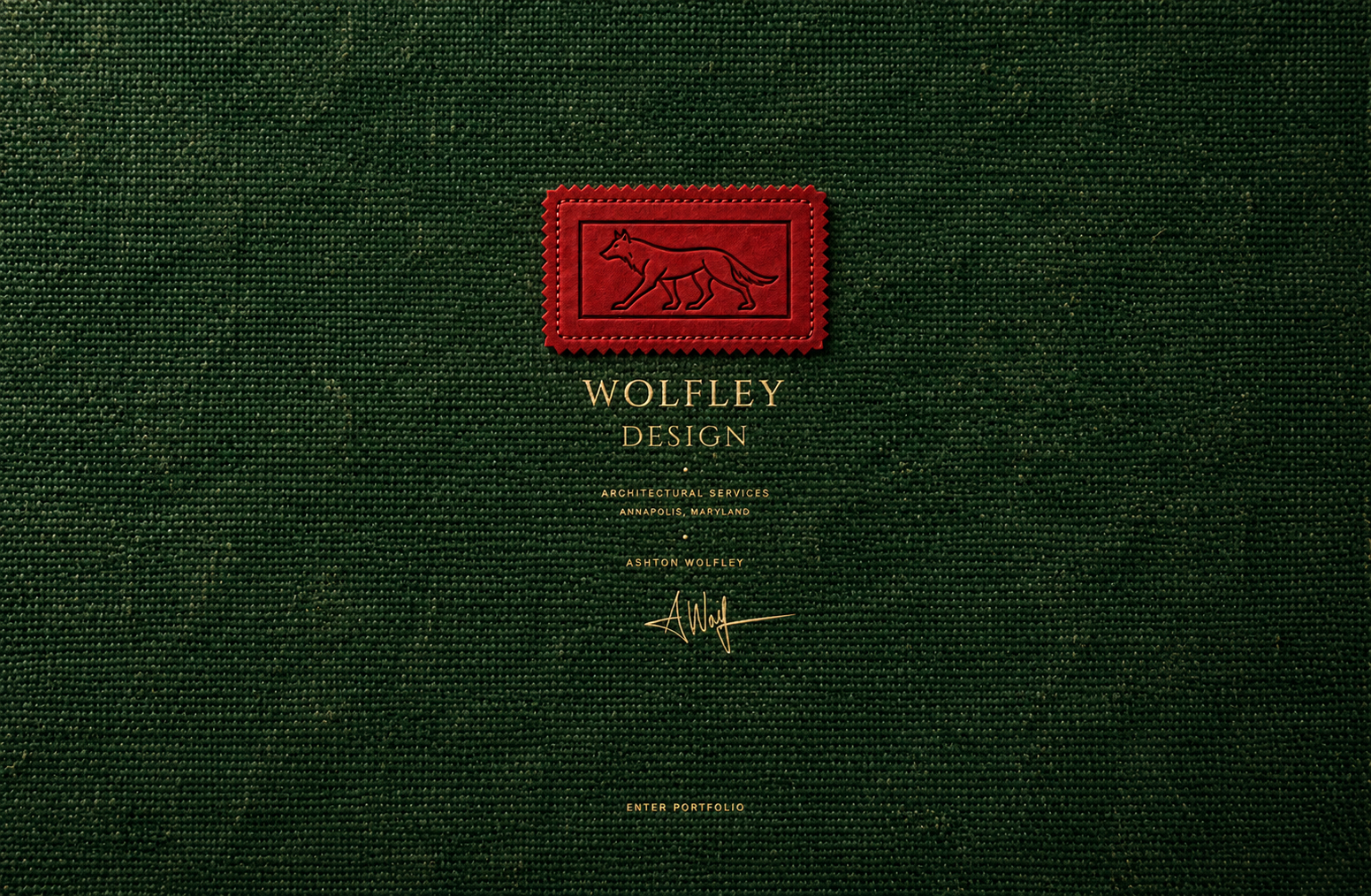 Red suede wolf cartouche sewn onto green canvas, with gold-stamped Wolfley Design lettering and Ashton Wolfley’s signature